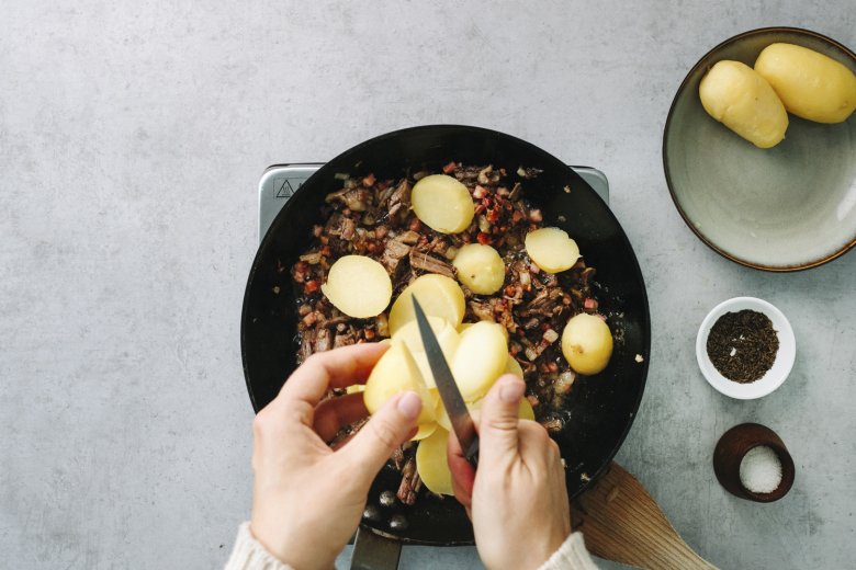 Step 1: In a large skillet, sauté the finely chopped onion with the diced bacon and beef. Add the sliced potatoes and continue to sauté.