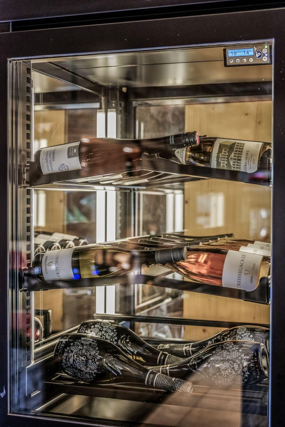 An elegant wine cabinet with various bottles of wine. The cabinet features a modern design and is well lit.