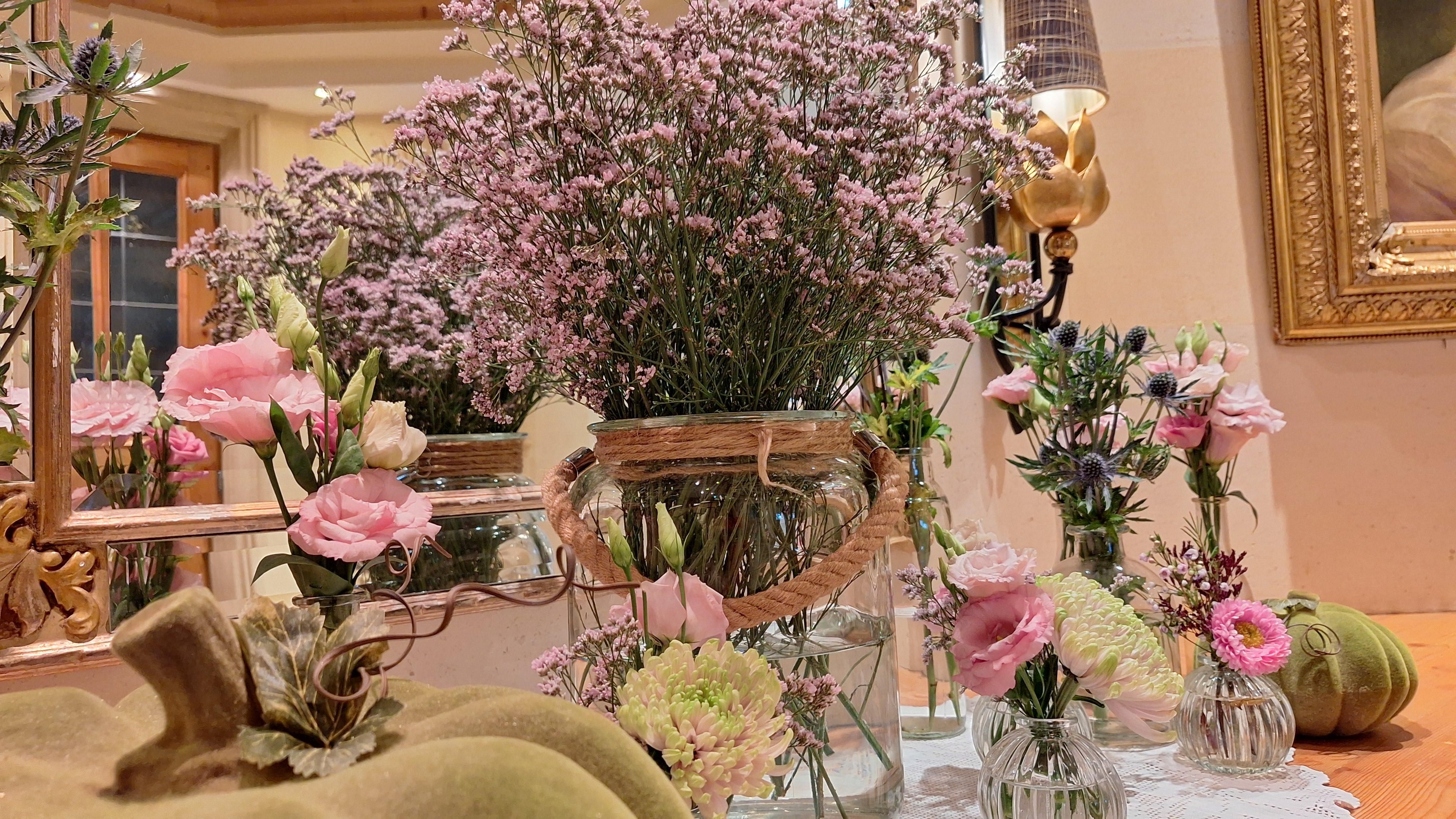 A beautiful table with various flower arrangements in glass vases. The colors are soft and the atmosphere feels inviting.