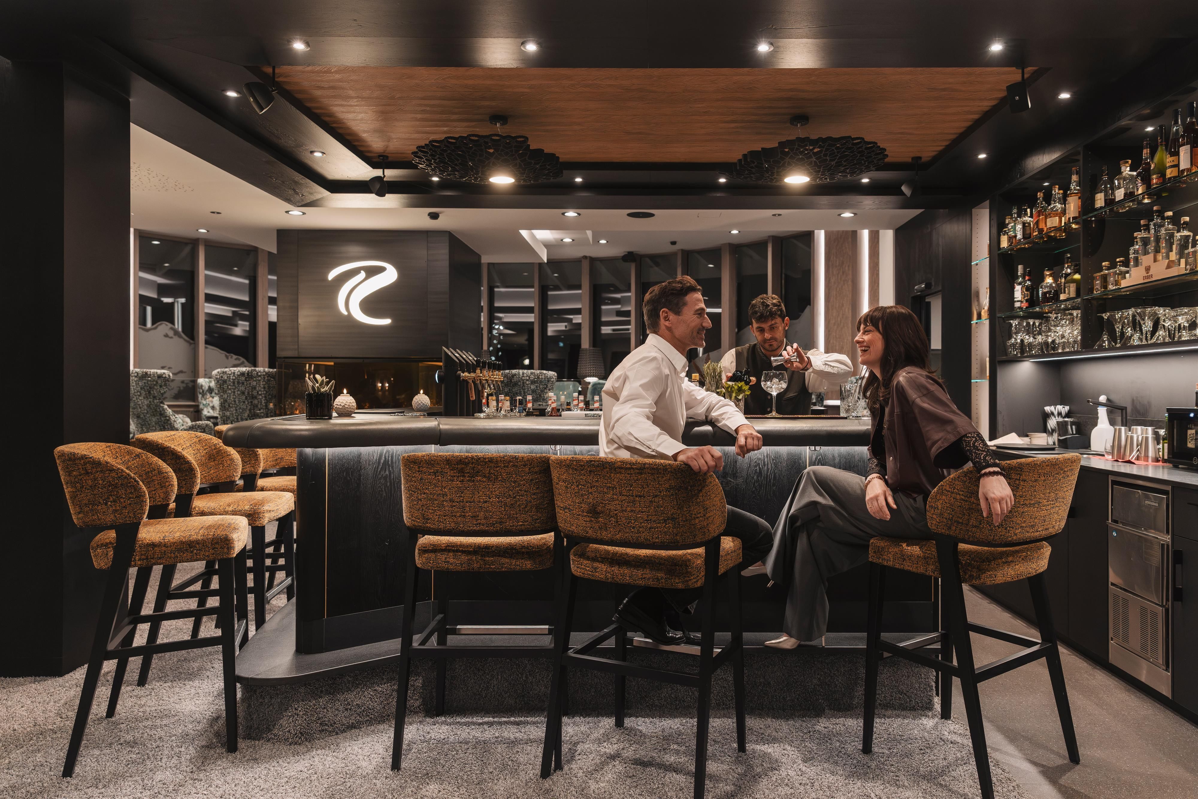An elegant bar with modern furniture and a stylish atmosphere. Two people are sitting at the bar counter and enjoying their time.