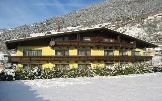 A charming yellow house in a snowy landscape. In the background, snow-covered mountains can be seen.