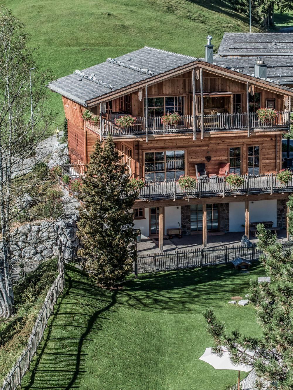 Main house in nature with several balconies.
Surrounded by green grass and trees.
