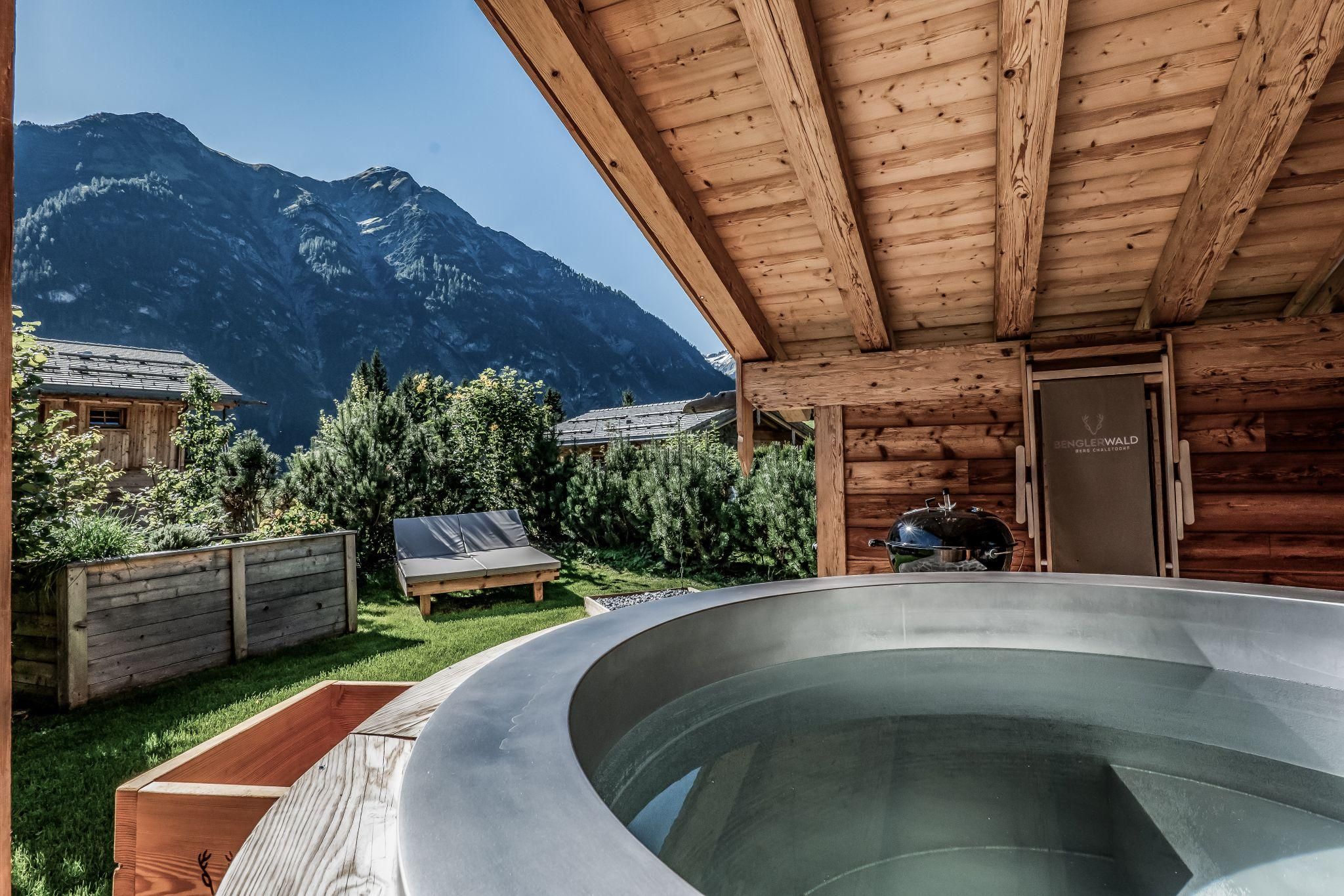 A beautiful outdoor area with a hot pot and a view of the mountains. The surroundings are green and inviting, ideal for relaxing.