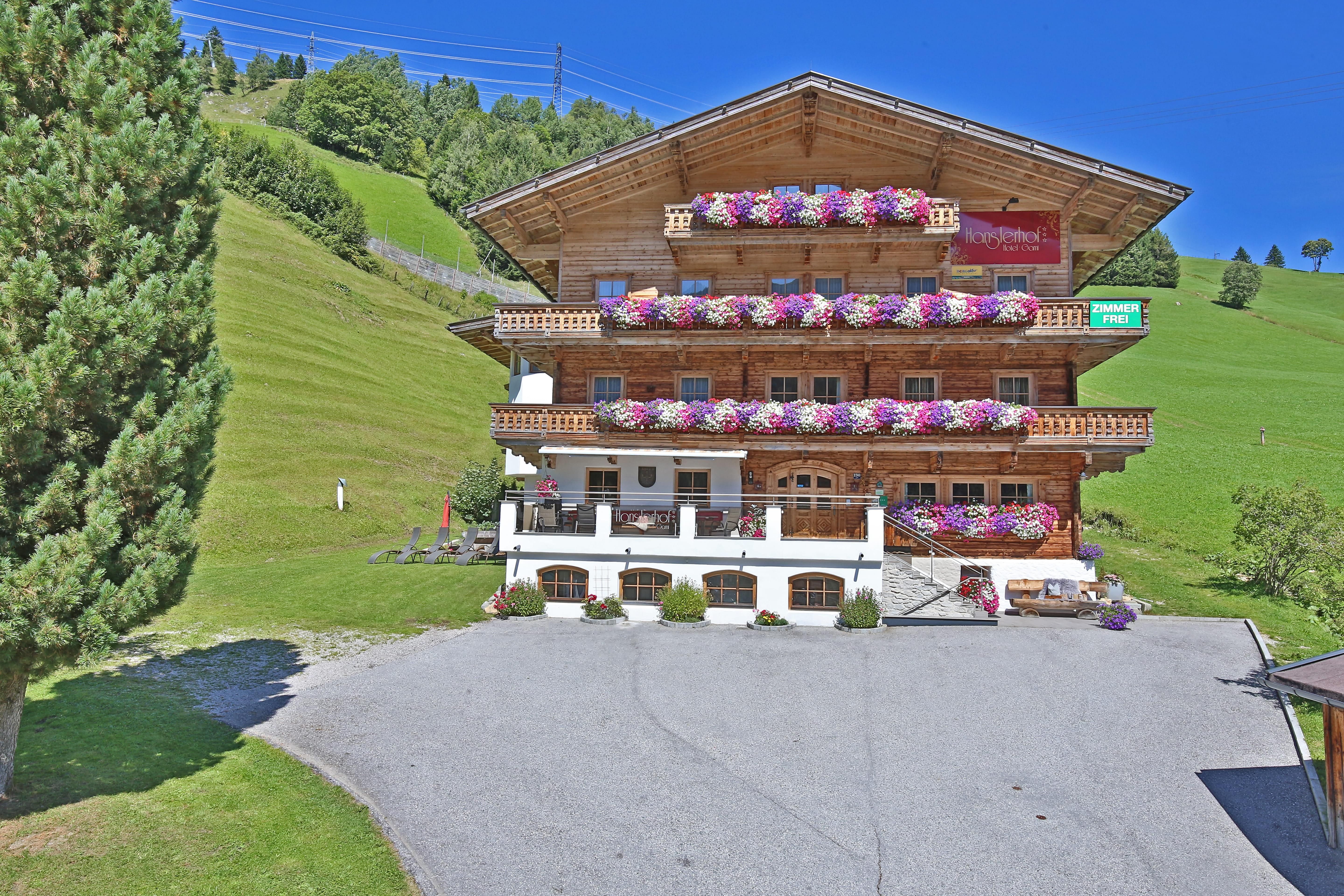 A charming wooden house with blooming balcony plants.
Surrounded by green meadows and a clear blue sky.