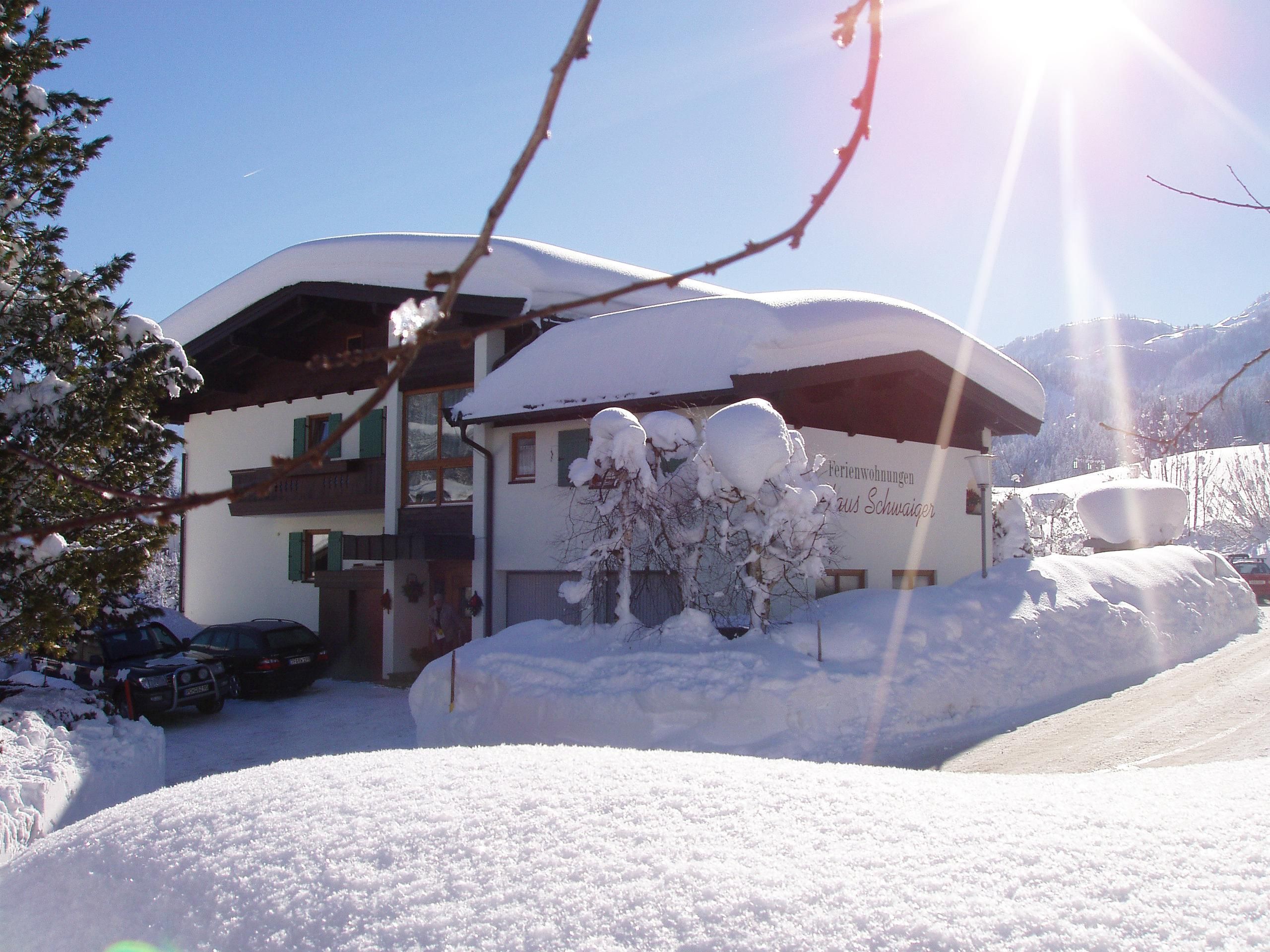 A beautiful house in the snow with a snow-covered property. The sun shines brightly over the winter landscape.