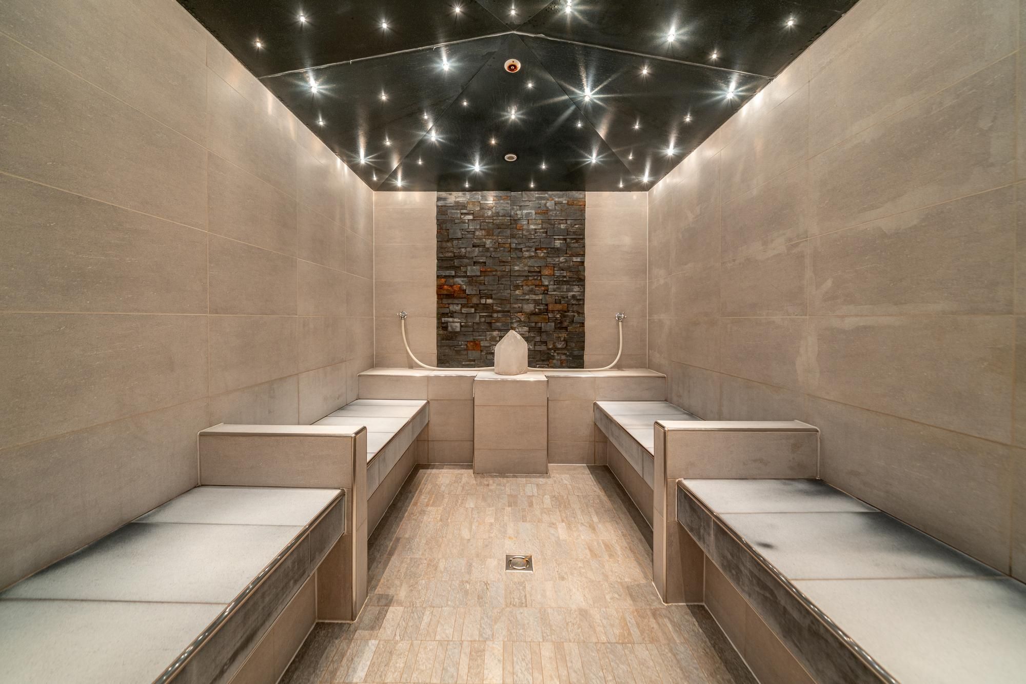An elegant, relaxing space with seating areas made of light stone. The ceiling is decorated with sparkling lights that create a calm atmosphere.
