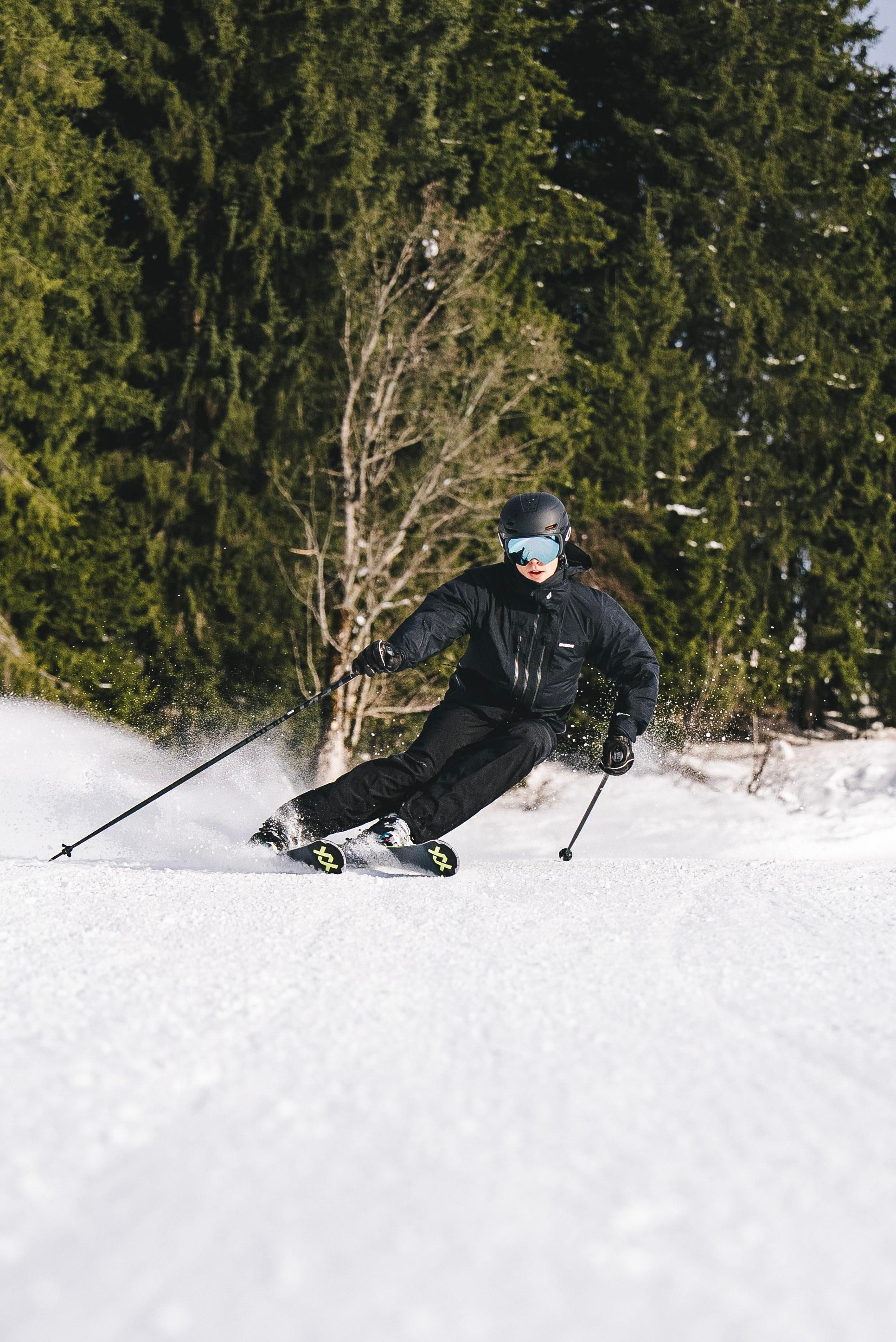 A skier is gliding through the snow in a forest. The surroundings are wintry and the trees are green.
