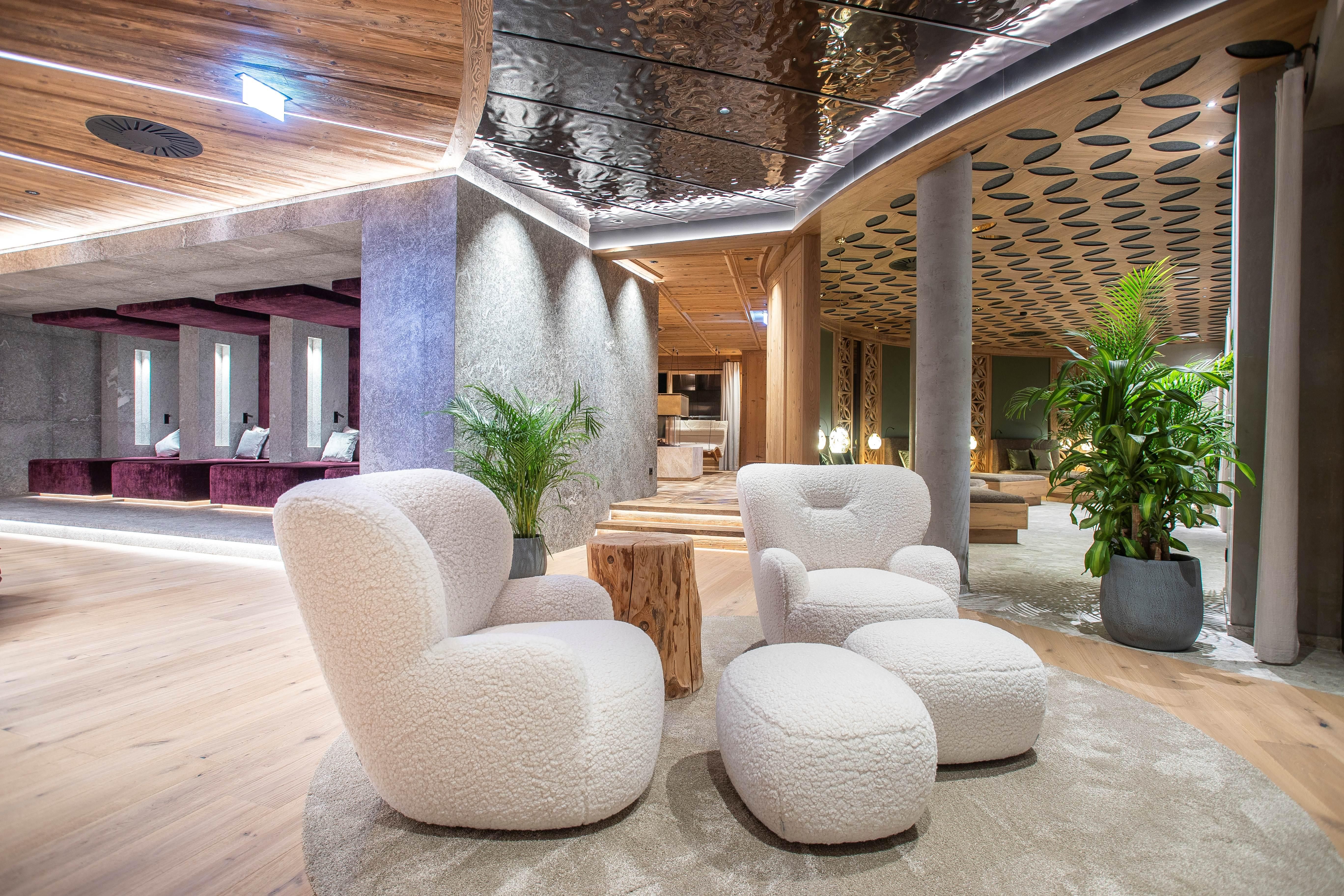 A modern reception area with comfortable, white armchairs and a small table. Green plants and soft lighting create an inviting atmosphere.
