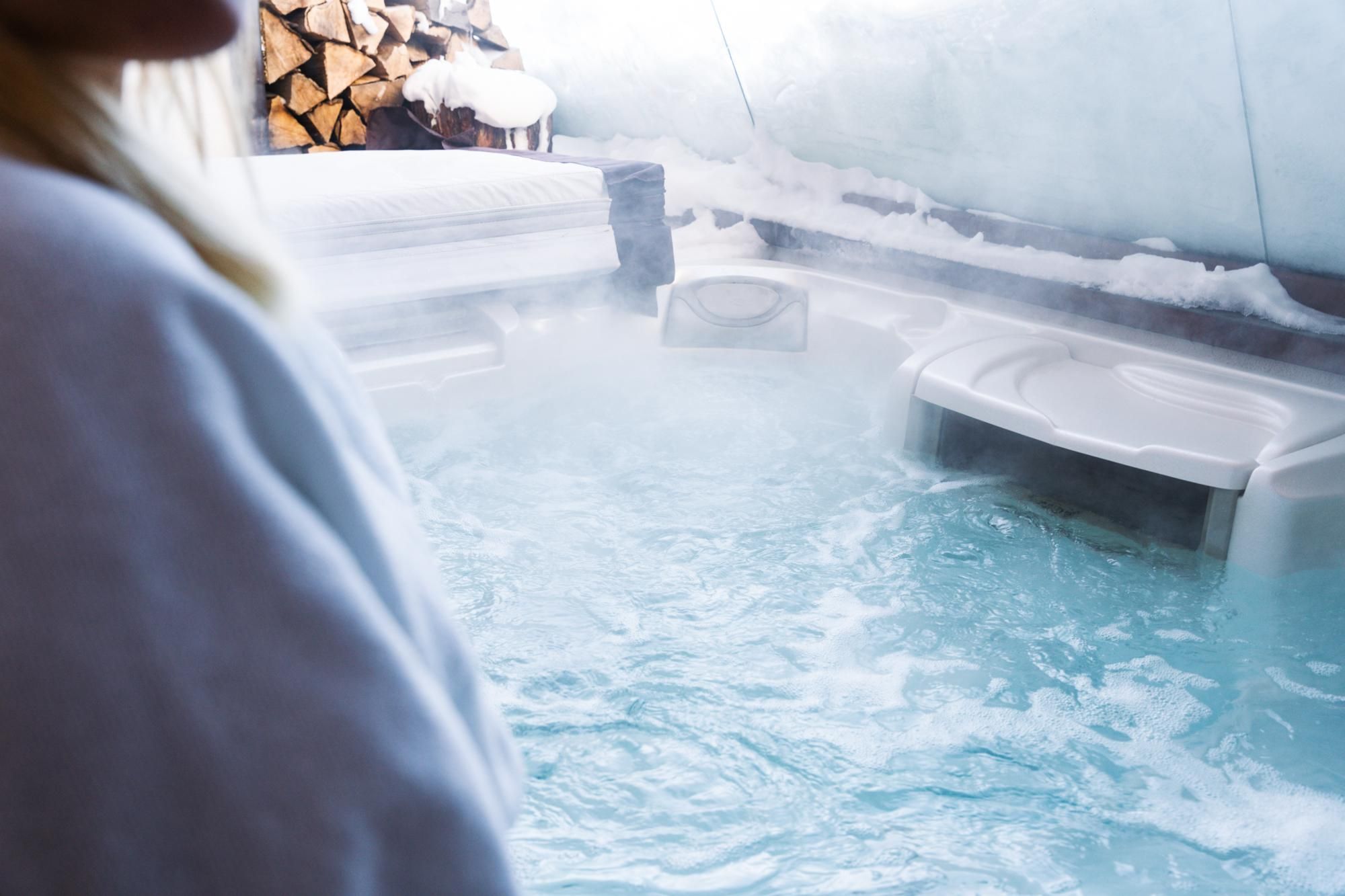 A relaxing hot tub with steaming water. In the background, some logs are visible.
