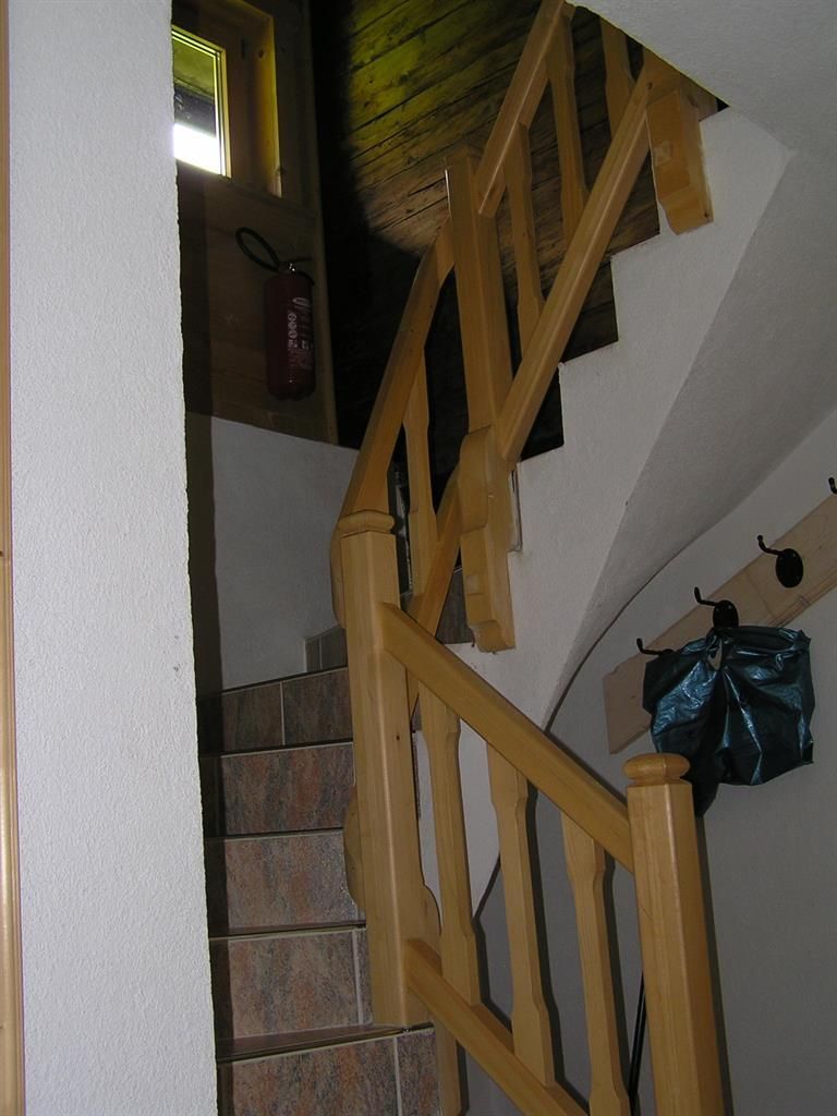 A staircase with a wooden railing leads upwards. The room is brightly lit and has a cozy atmosphere.