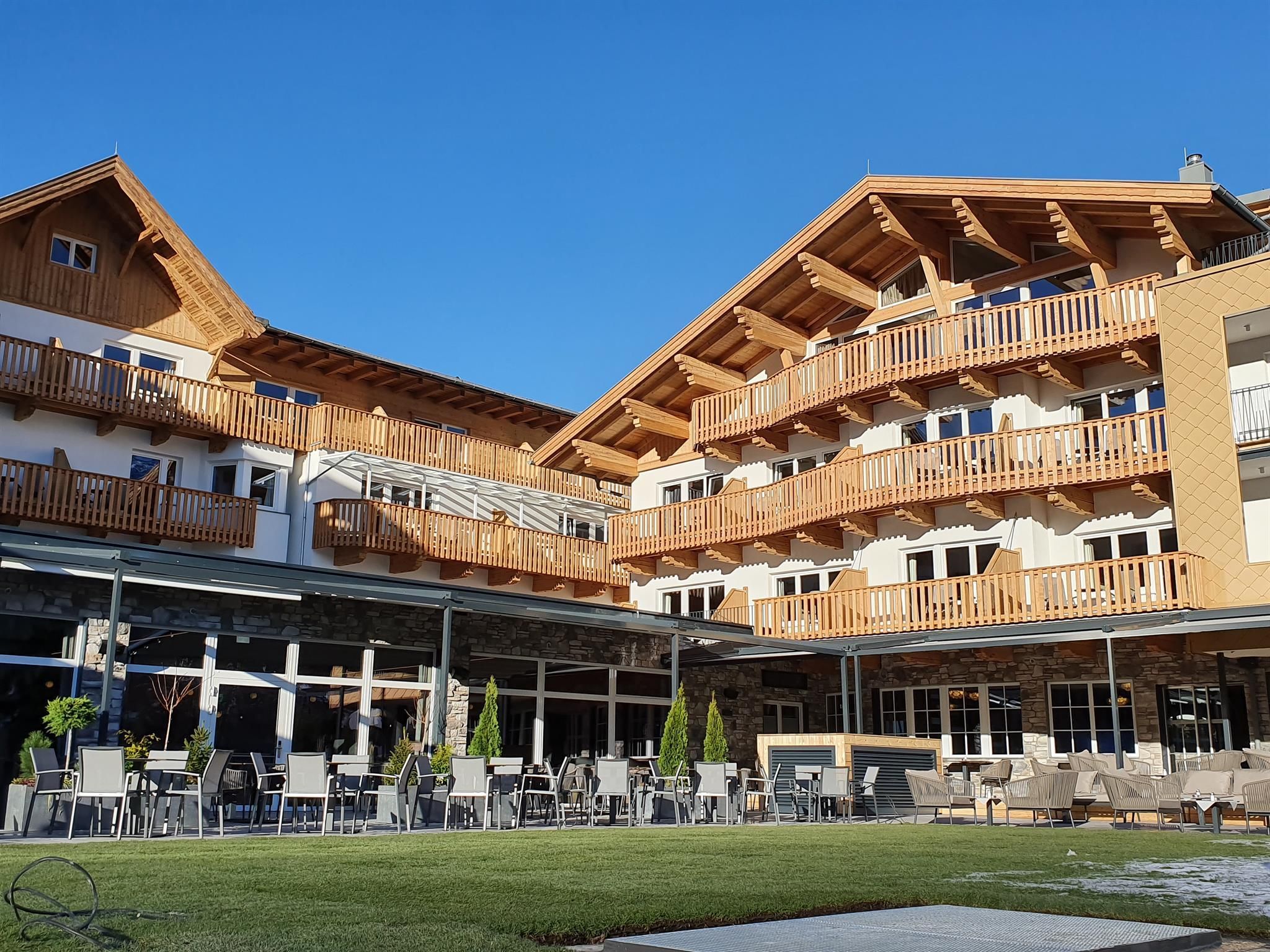A modern hotel building with several balconies and a large terrace. The sky is clear and blue, creating an inviting atmosphere.