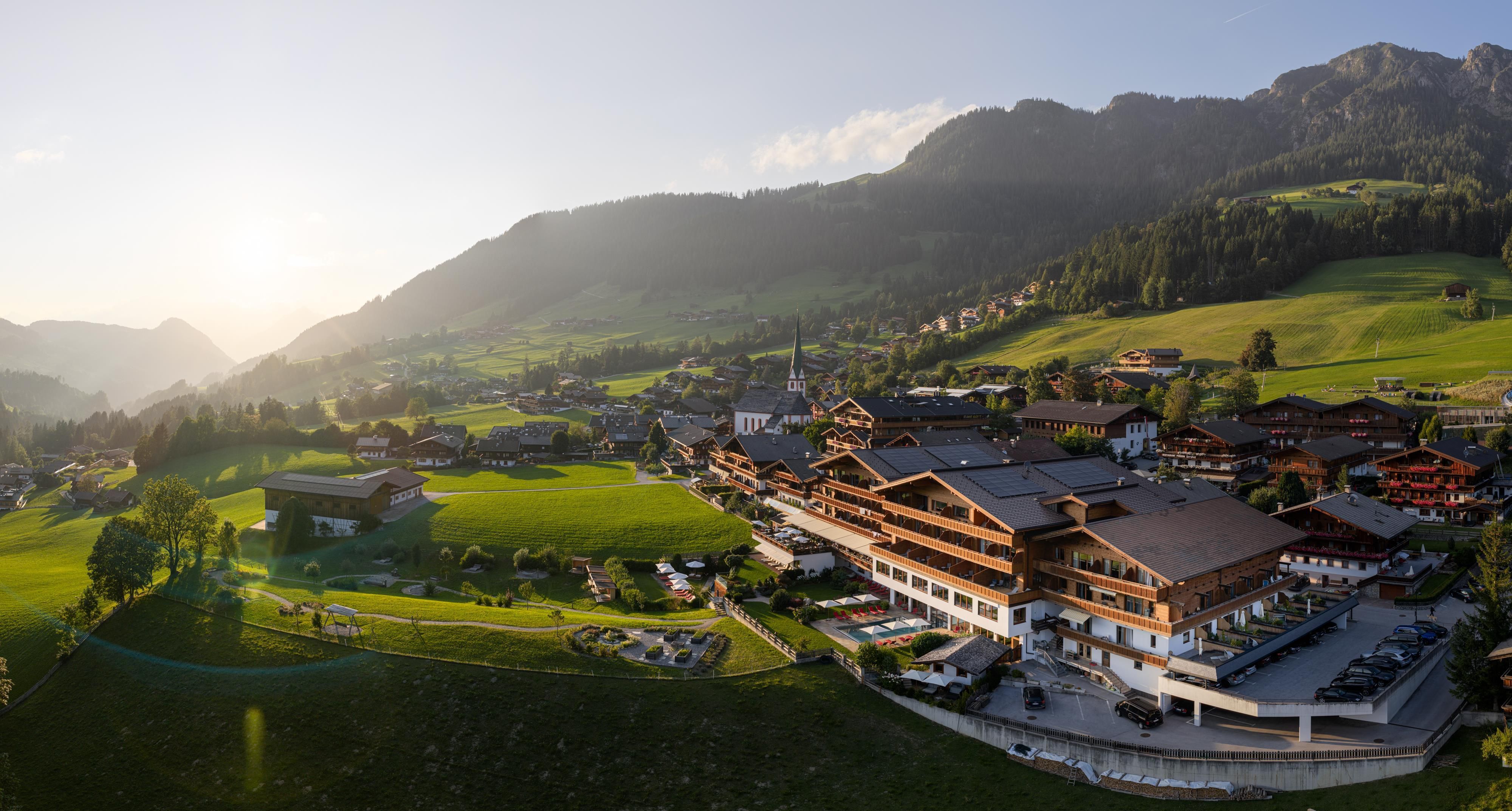 A picturesque landscape with green meadows and mountains in the background. In the foreground is a charming village with traditional buildings.