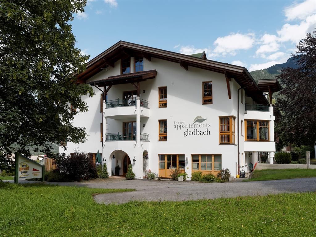 A charming building with multiple floors and a balcony. Surrounded by green meadows and trees.