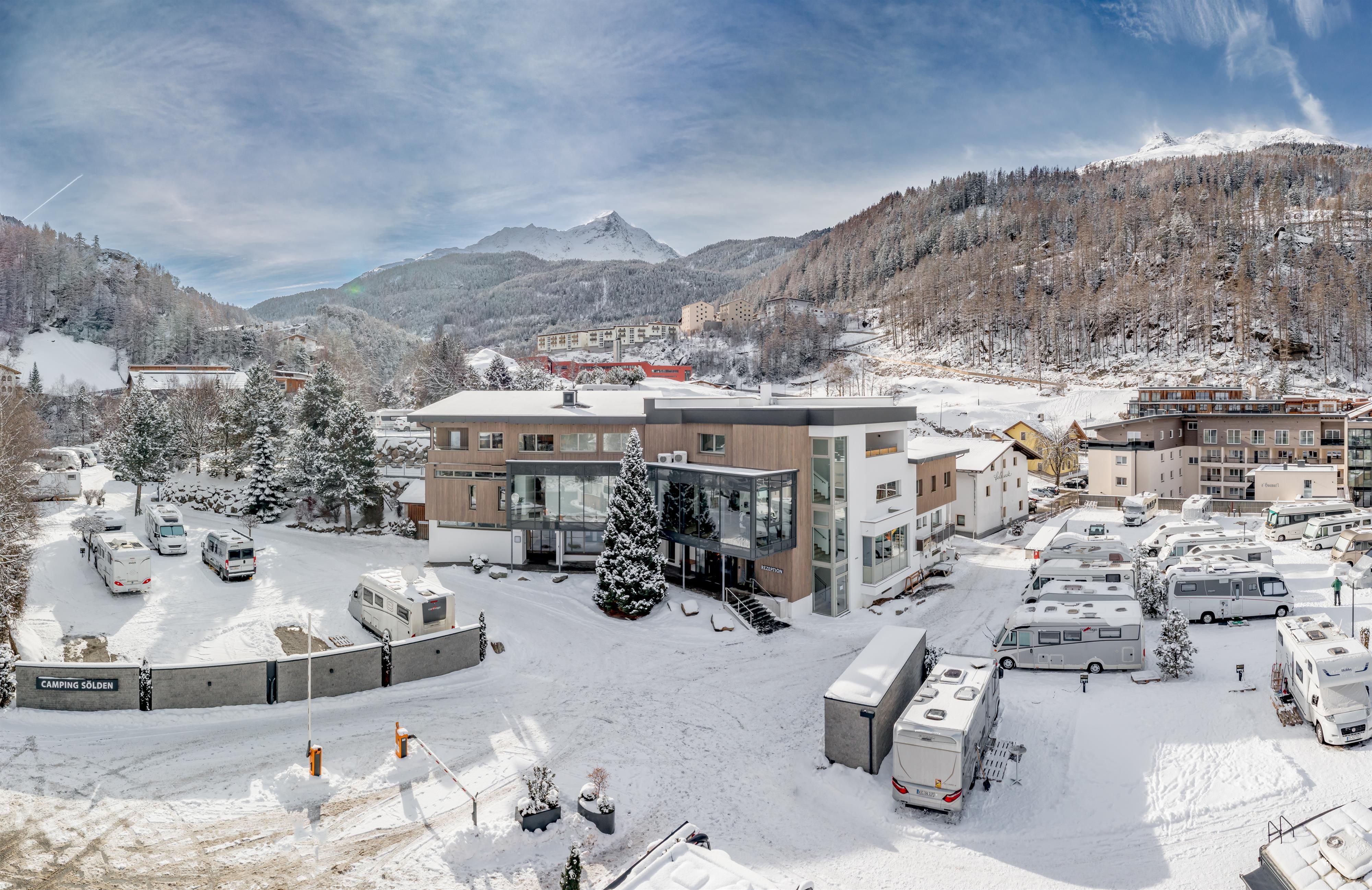 A snowy village in the mountains with modern buildings. The surroundings are calm and picturesque, surrounded by snow-covered mountains.
