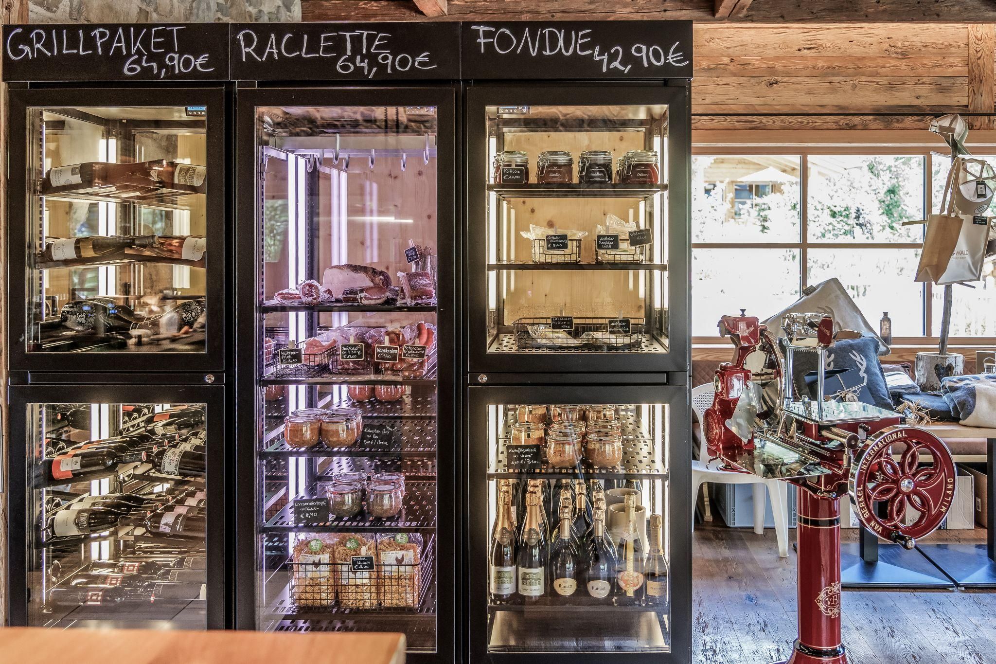 A cozy interior with refrigerators offering various food and drinks. The price tags for grill package, raclette, and fondue are clearly visible.