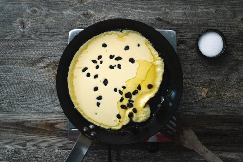 Melt butter in a heated pan, pour in the batter and scatter raisins over the top.