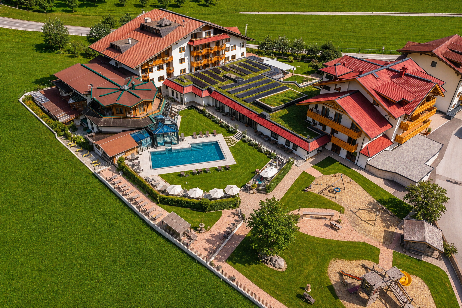 A colorful hotel with several buildings, pools, and a large garden. The outdoor area features playgrounds and cozy seating areas.
