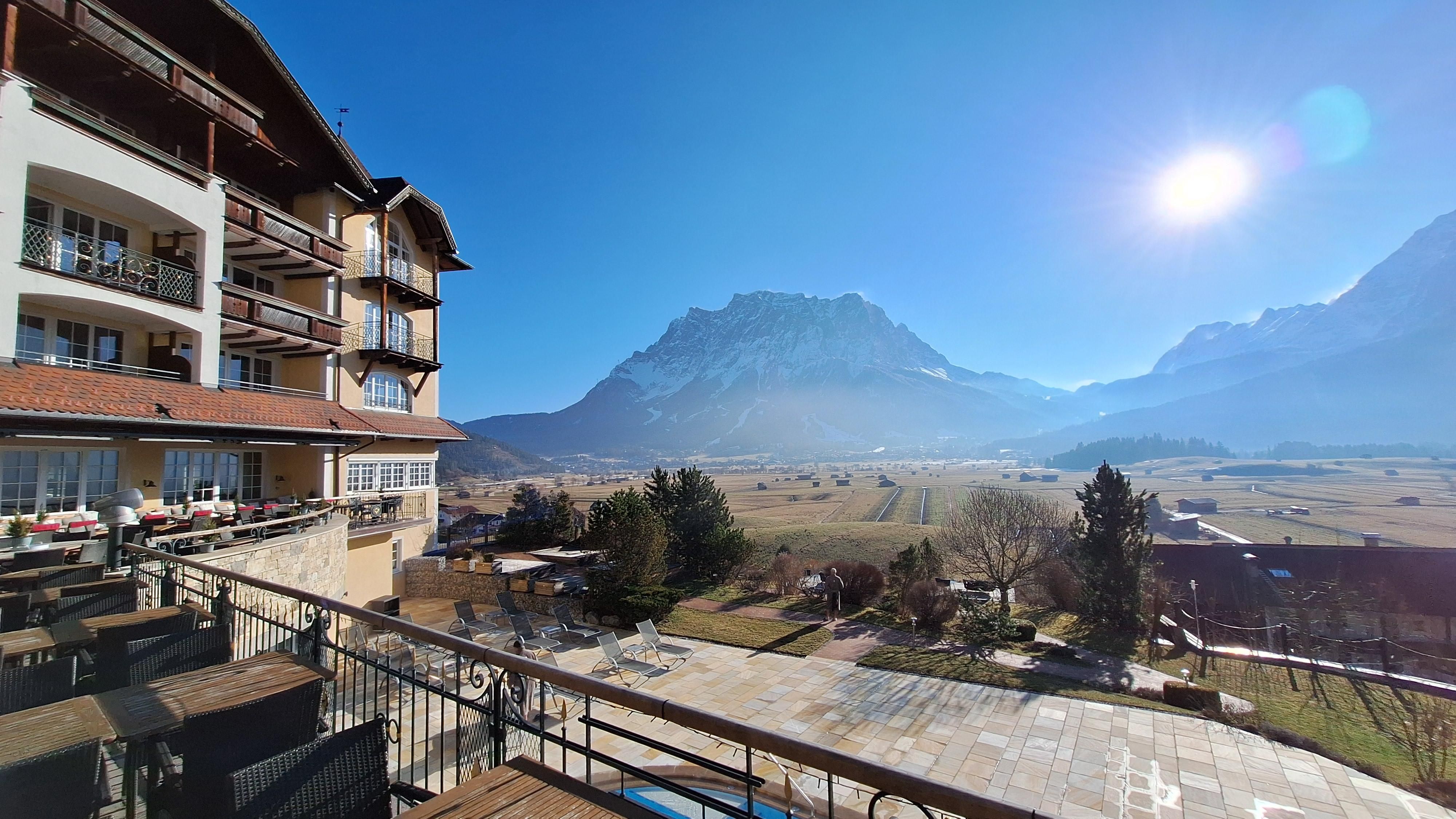 A beautiful hotel with a view of the mountains and the clear, blue sky. The landscape is green and inviting.