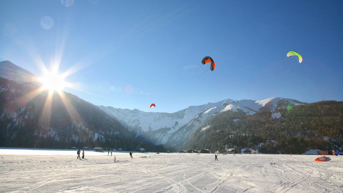 As soon as the wind begins to blow, scores of snowkites transform the northern shore of Lake Achensee into a mosaic of colour. This popular new sport can be picked up quickly even by intermediate skiers and snowboarders., © Achensee Tourismus