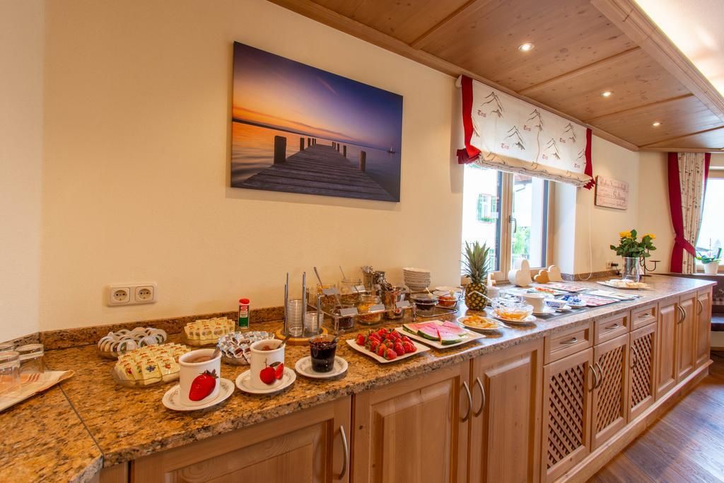 An inviting breakfast setting with a variety of foods and drinks on a wooden counter. In the background, there is a picture of a sunset over a dock.