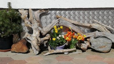 Treibholz mit Blumen und Latschen vor Erker