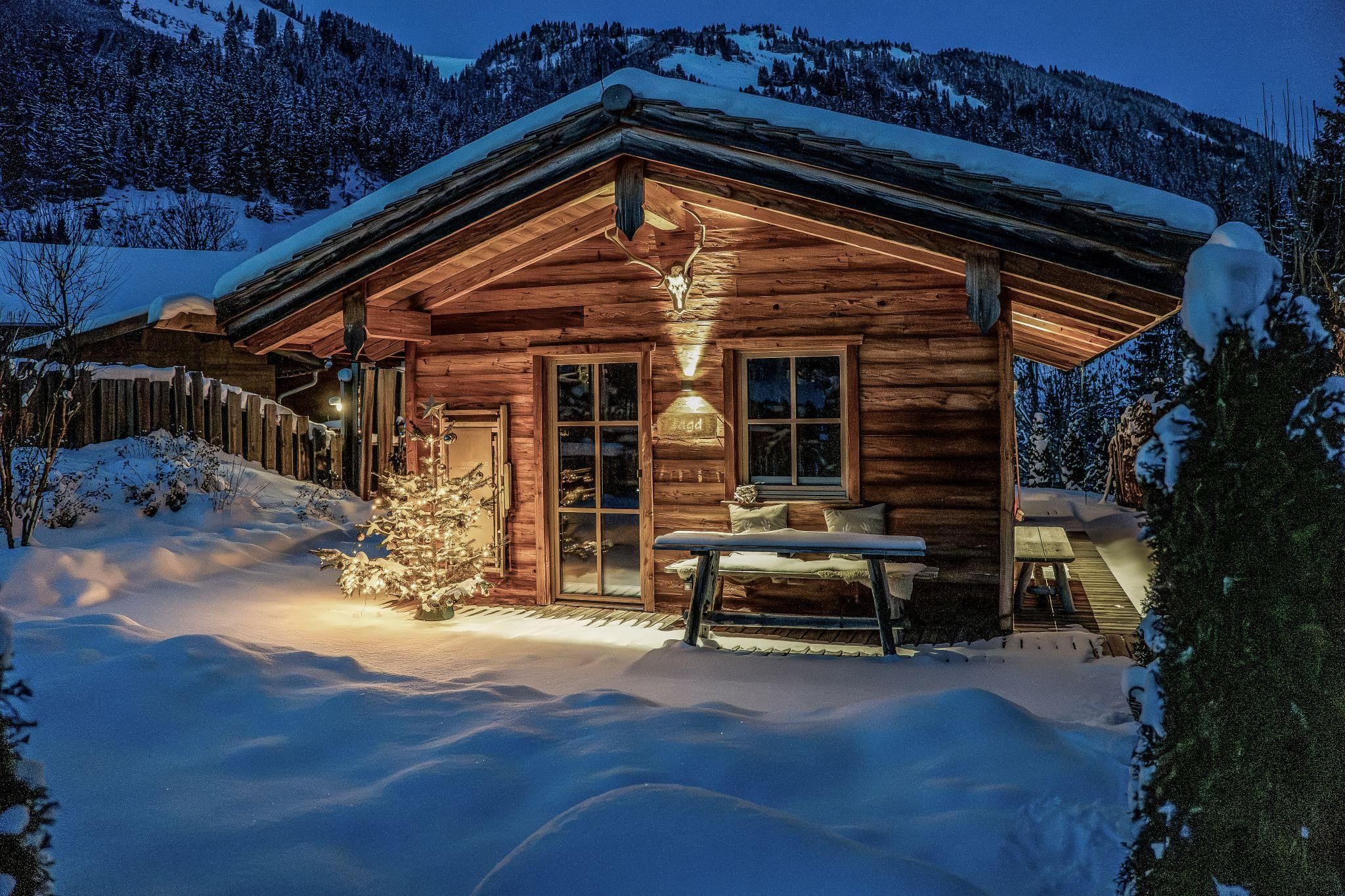 A cozy chalet in the snowy landscape. The surroundings are quiet and the sky can be seen at night.