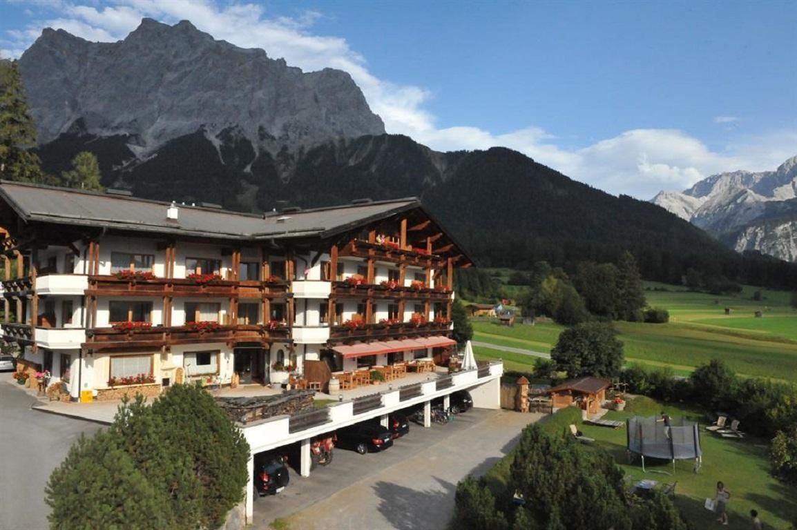 A traditional hotel in the mountains with balconies and a beautiful view. The surroundings are green and picturesque.