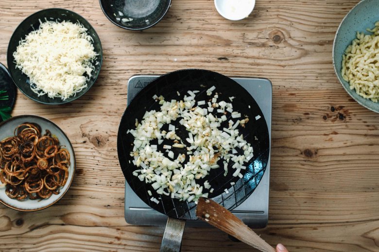 Step 4: In a pan, saut&eacute; the diced onions with a knob of butter, add the Sp&auml;tzle and stir in the cheese bit by bit. Mix well and allow the cheese to melt.