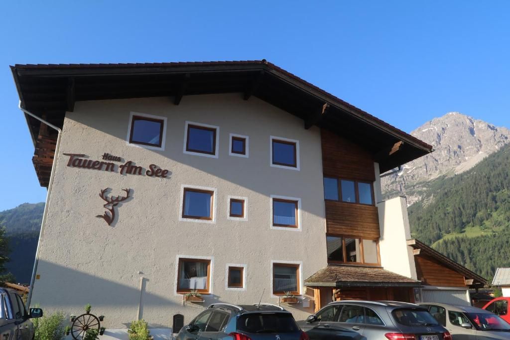 A cozy inn called "Tavern by the Lake" with modern windows and a beautiful mountain view. Parking is available in front of the building.